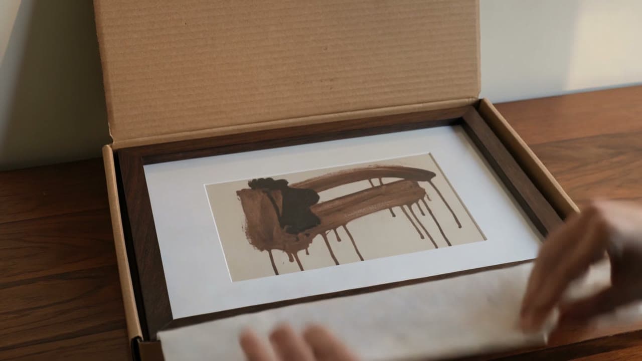 A framed art print on a wall in a sunlit interior